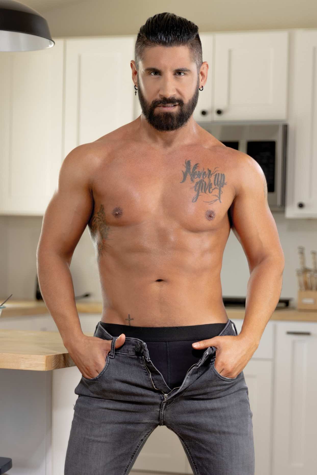 Justin Jett posing in a sophisticated studio setting, showcasing his black hair, signature beard, and muscular 5'11 frame in a high-quality masculine portrait.