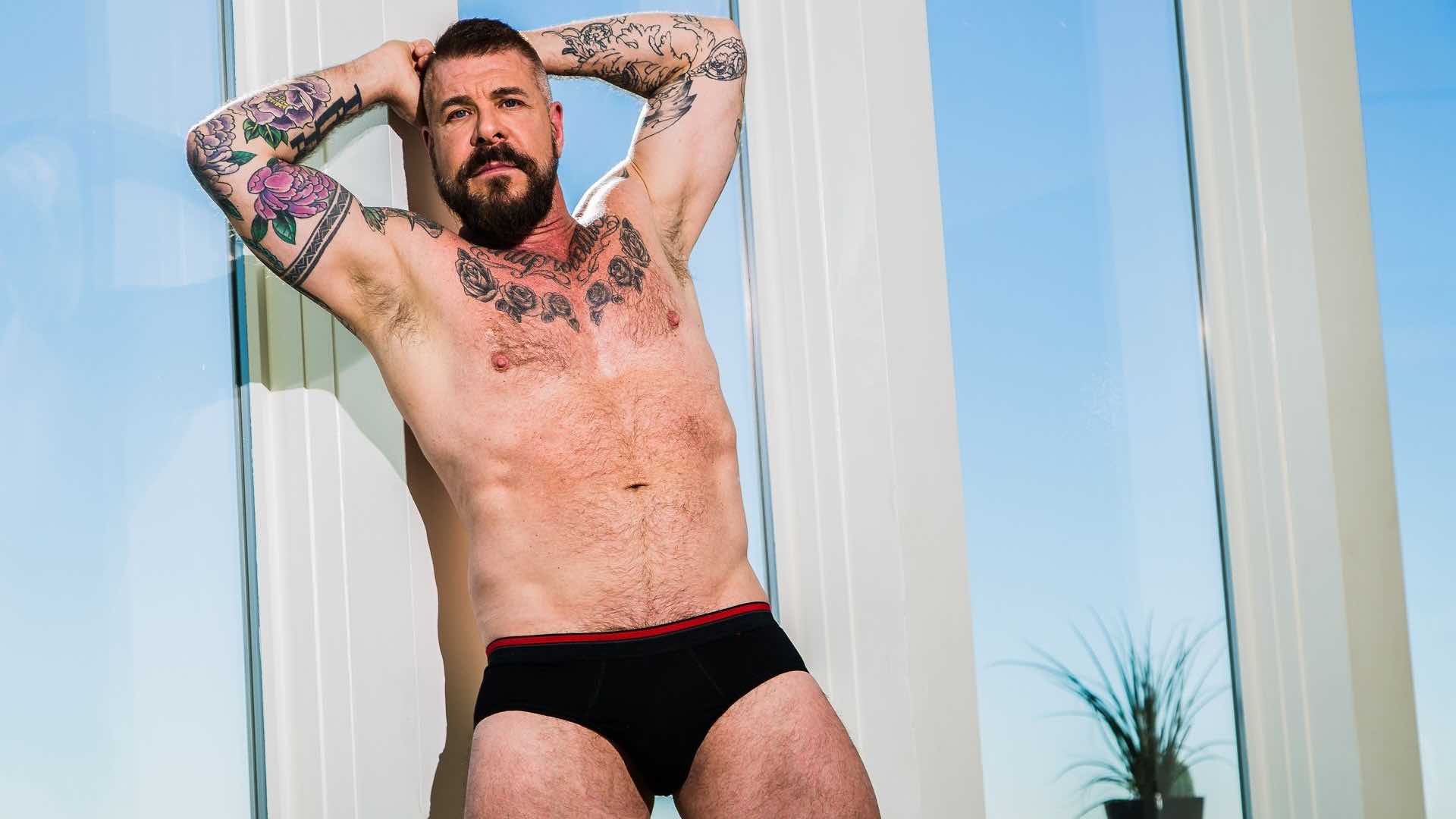 A sophisticated and tattooed male influencer managing his digital brand, capturing the professional and mature spirit of Rocco Steele.